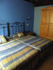 een slaapkamer met een groot bed met een blauwe muur bij Casa De Aldea Fonfria in Las Vegas De Cardeo