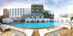 a hotel swimming pool with white chairs and a building at Amoureux Resort in Jeju