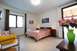 1 dormitorio con 1 cama y un jarrón de flores sobre una mesa en Bio-Agriturismo masseria La Palombara, en Salve