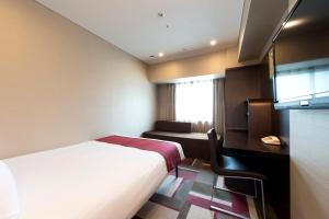 a hotel room with two beds and a television at Hotel Villa Fontaine Kobe Sannomiya in Kobe