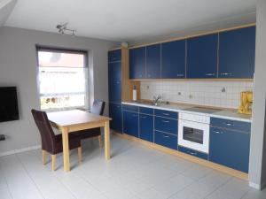 クックスハーフェンにあるAppartement Stader Str. 3のキッチン(青いキャビネット、木製テーブル付)