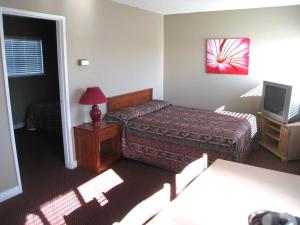 a hotel room with a bed and a television at Beach Grove Motel in Tsawwassen