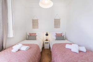 リスボンにあるLovelyStay - Bonsai Light and Comfort flatの白とピンクのシーツが備わる客室で、ツインベッド2台が付いています。