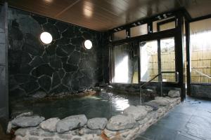 a pool of water in a room with a stone wall at Rangetsu in Kyoto