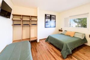 1 dormitorio con 1 cama y TV de pantalla plana en La Tosca Hostel en Puerto Madryn