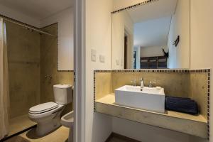 een badkamer met een wastafel, een toilet en een spiegel bij La Tosca Hostel in Puerto Madryn