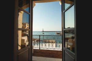 una puerta abierta a un balcón con vistas al océano en Chania Inn en La Canea