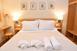 Un dormitorio con una cama blanca con toallas. en Onar Pension, en Nauplia