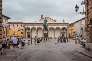 Un gruppo di persone che camminano intorno a un edificio con una statua. di Canto dei Servi a Firenze