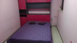 - une petite chambre avec un lit violet et des armoires rouges dans l'établissement Luxury Apartment Uzunov, à Hisarya