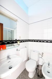 a white bathroom with a toilet and a sink at Pensao O Laranjeira in Viana do Castelo