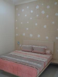 a bedroom with a bed with pink sheets and pillows at Cerah Hotel in Paiton