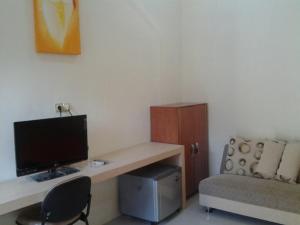 ein Zimmer mit einem Schreibtisch mit Computer und einer Couch in der Unterkunft Cerah Hotel in Paiton