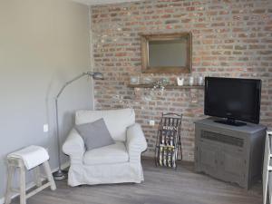 a living room with a chair and a television at Hoeve Schevey in Mechelen