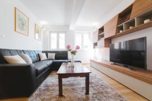 a living room with a black couch and a tv at City Center LUX Apartment "TONCI" in Omiš