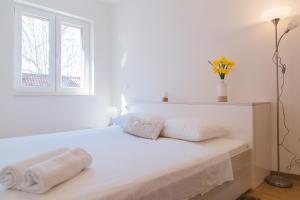 a white bedroom with a bed with two towels on it at City Center LUX Apartment "TONCI" in Omiš
