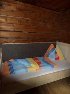 Bett in einem Zimmer mit Holzwänden in der Unterkunft Almhütte Senfter in Innervillgraten