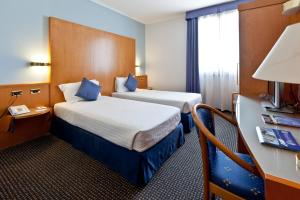 Pokój hotelowy z 2 łóżkami i biurkiem w obiekcie UNA HOTELS Occhiobello w mieście Occhiobello