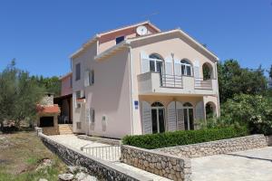 a large white house with a stone wall at Apartments Matlovac in Ždrelac