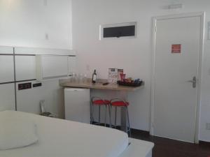 a kitchen with a counter and two red stools at Prime Motel in Criciúma