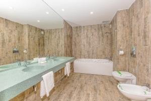 a bathroom with two sinks and a tub and a toilet at Hotel Riviera in Mamaia