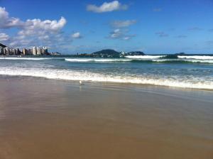 a beach with waves and buildings in the background at Vista ao Mar & Lazer Total in Guarujá