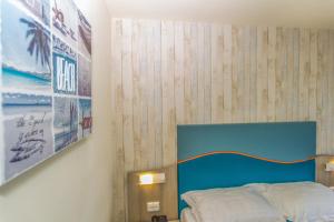 a bedroom with a bed with a blue headboard and a poster at Hotel Riviera in Mamaia