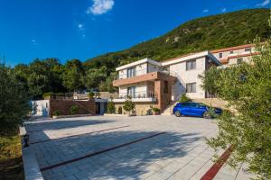 una casa con un coche azul aparcado en una entrada en Villa Svinjista en Budva