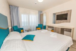 a bedroom with a white bed and blue chairs at Hotel Riviera in Mamaia