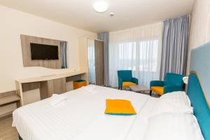 a hotel room with a white bed and blue chairs at Hotel Riviera in Mamaia