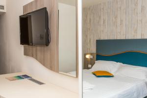 a bedroom with a bed with a mirror and a tv at Hotel Riviera in Mamaia