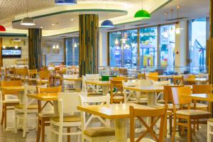 a restaurant with tables and chairs and windows at Hotel Riviera in Mamaia