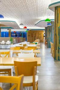 a dining room with tables and chairs and lights at Hotel Riviera in Mamaia