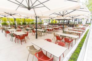 an outdoor patio with tables and chairs and umbrellas at Hotel Riviera in Mamaia