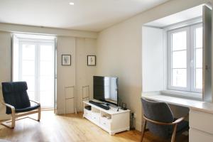 uma sala de estar com televisão e duas cadeiras em Boavista Bike Apartment em Lisboa