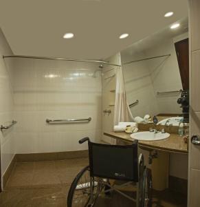 silla de ruedas en el baño con lavabo y espejo en Wyndham Sao Paulo Paulista en São Paulo