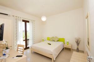 a white bedroom with a bed and a table at Villa Elios Guesthouse in Birgi Vecchi