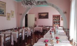 ラパッロにあるAlbergo Bandoniのダイニングルーム(白いテーブル、椅子、シャンデリア付)