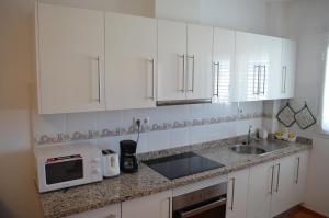 eine Küche mit weißen Schränken, einer Spüle und einer Mikrowelle in der Unterkunft VV Sarmiento in Vecindario