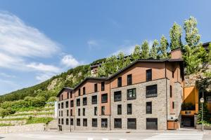 a large brick building with a mountain in the background at Apartamentos Prat de les Molleres in Soldeu
