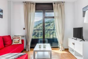 ein Wohnzimmer mit einem roten Sofa und einem großen Fenster in der Unterkunft Apartamentos Prat de les Molleres in Soldeu