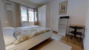 ein Schlafzimmer mit einem Bett und einem Tisch und einem Fenster in der Unterkunft Paravicini in St. Moritz