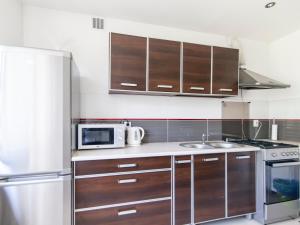 cocina con armarios de madera y microondas en Pałacowa Condominium, en Białystok