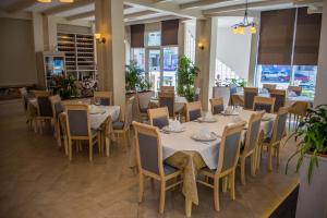 un restaurante con mesas y sillas blancas y ventanas en Hotel Vila Koral, en Durrës