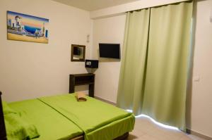 een slaapkamer met een groen bed en een groen gordijn bij Maestro Apartments Faliraki in Faliraki