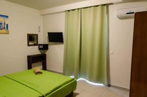 a bedroom with a green curtain and a bed at Maestro Apartments Faliraki in Faliraki