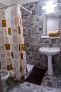 y baño con lavabo, aseo y cortina de ducha. en Maestro Apartments Faliraki en Faliraki