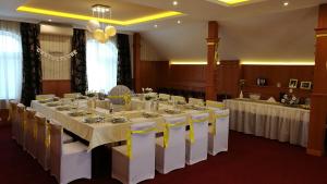 a room with a long table with white tables and chairs at Patyi Étterem és Hotel in Bögöte