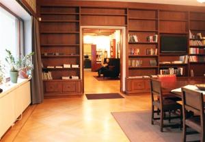 a living room with a dining room table and bookshelves at Art Hotel Honkahovi in Mänttä