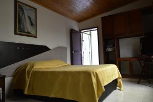 a bedroom with a bed with a yellow blanket on it at Hotel El Principe in Ocaña